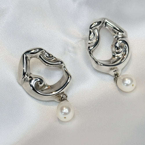Silver earrings with pearl drops on a white fabric background
