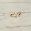 Gold ring with two pink gemstones on a white marble background