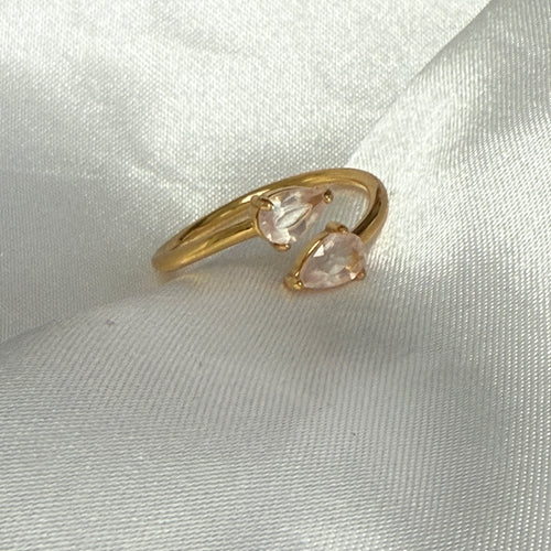 Gold ring with pink gemstones on a light fabric background