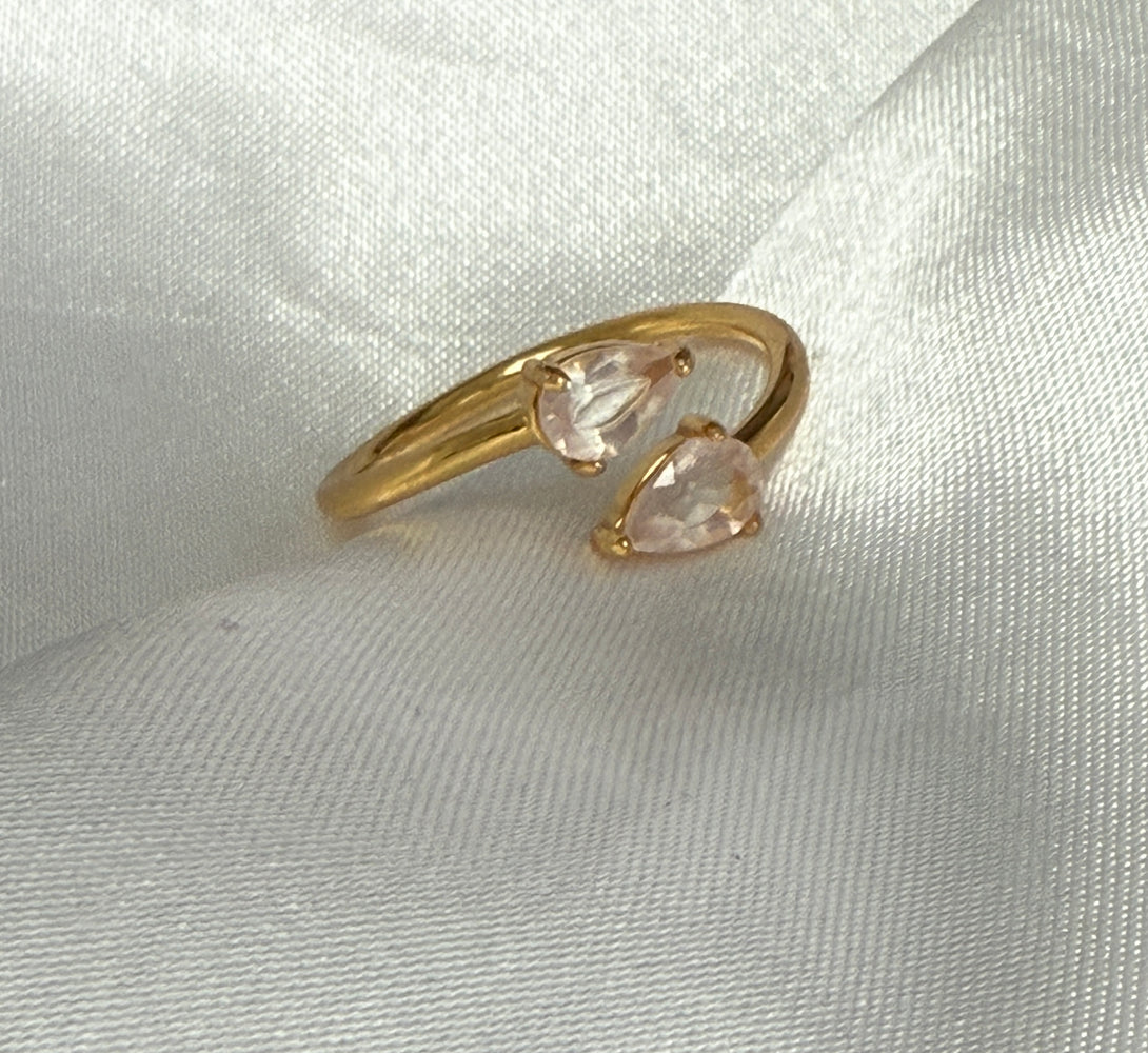 Gold ring with pink gemstones on a light fabric background