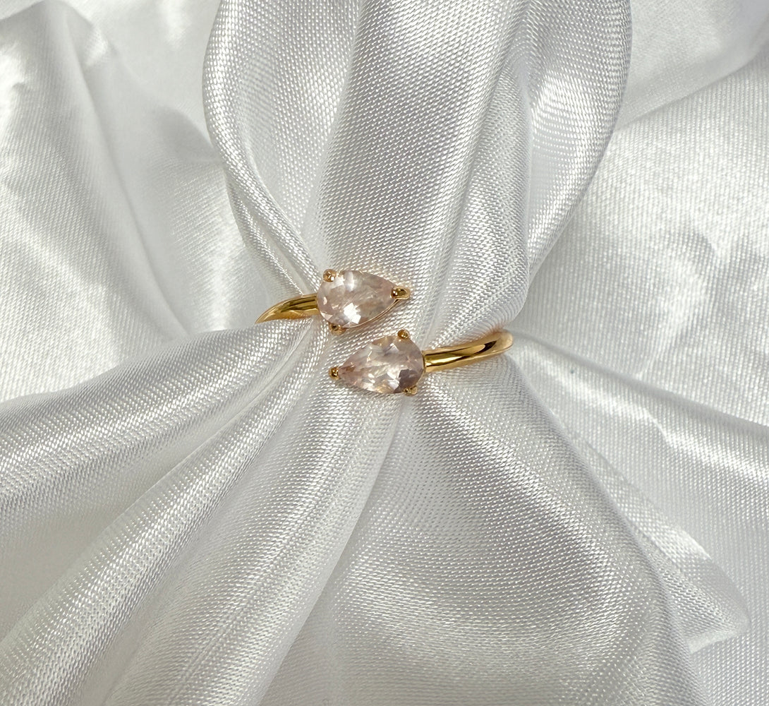 Gold ring with pink gemstones on a white fabric background