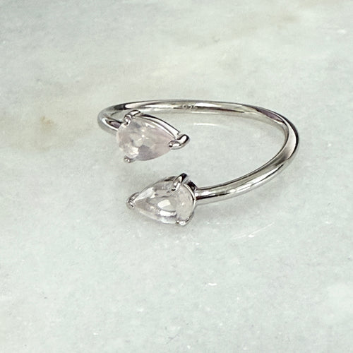 Silver open ring with two clear gemstones on a light gray background