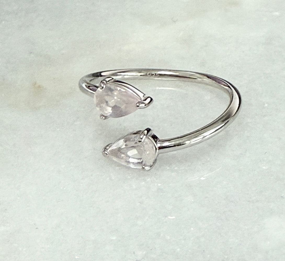 Silver open ring with two clear gemstones on a light gray background