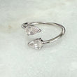 Silver open ring with two clear gemstones on a light gray background