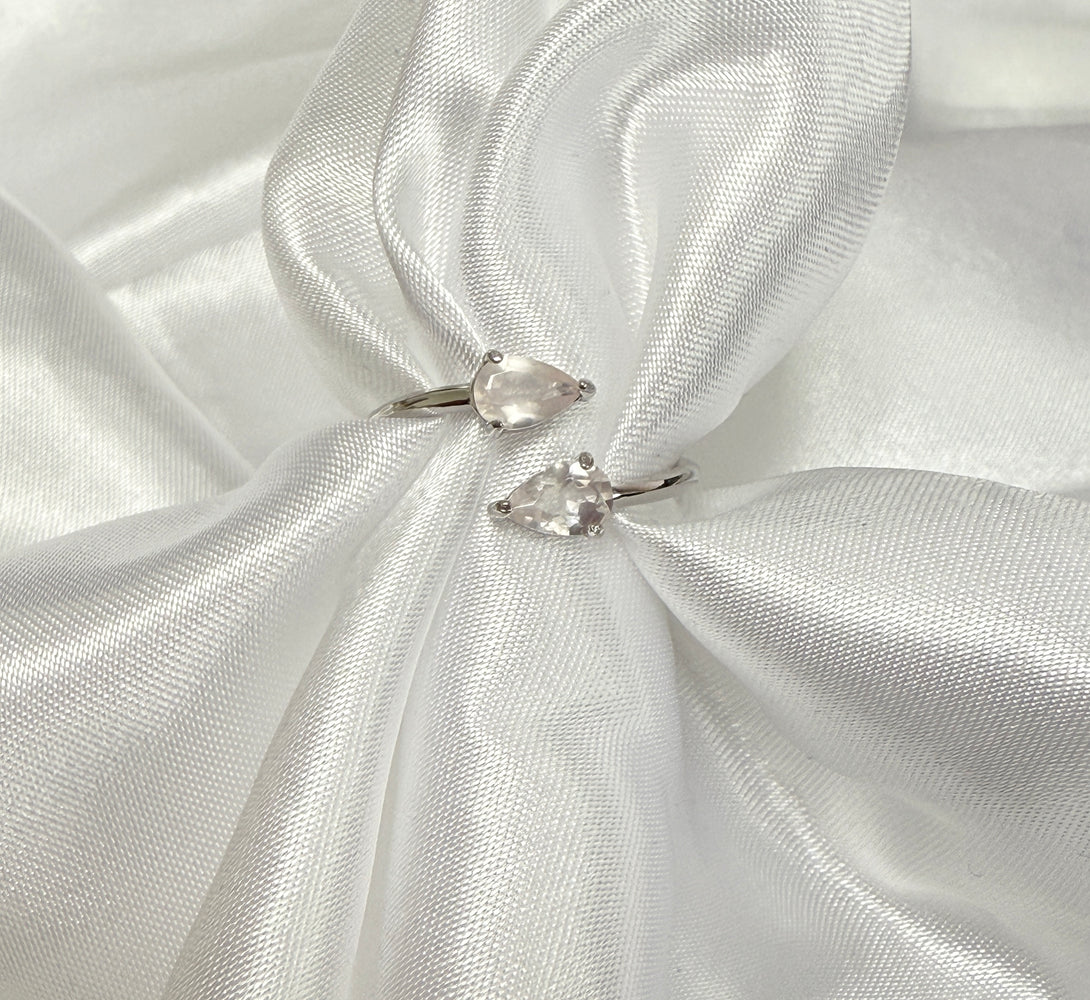 Two pear-shaped diamond rings on a white satin fabric background
