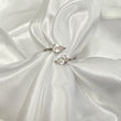 Two pear-shaped diamond rings on a white satin fabric background